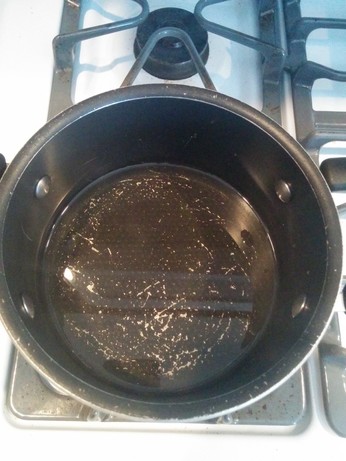 A pot on a stove, containing a mixture of water and honey