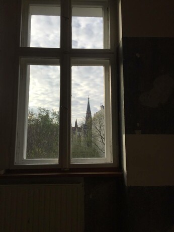 an image of a large church tower out the window in the morning with small birds flying around it 